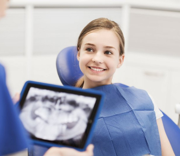 Dentist reviewing young girl’s dental X-rays 
