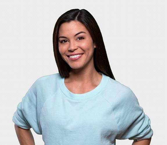 Woman in a blue sweater smiling after clear aligner treatment 