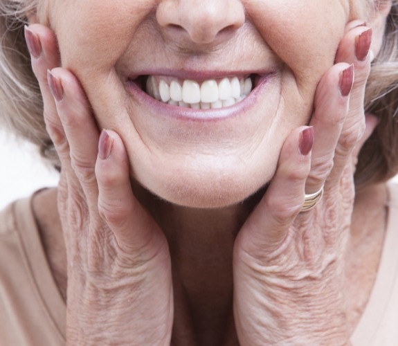 Smiling senior woman touching her face