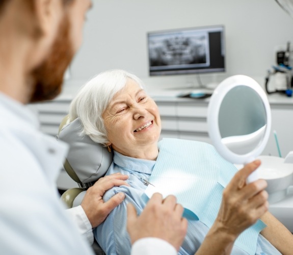 Senior dental patient admiring her smile in a mirror