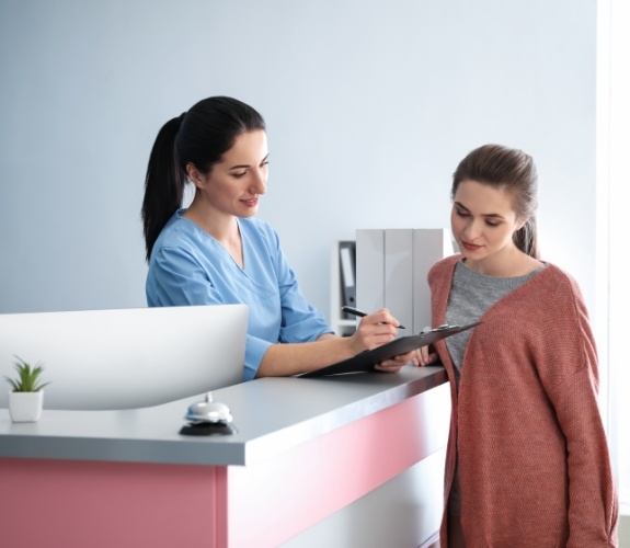 Dental team member showing a clipboard to a patient