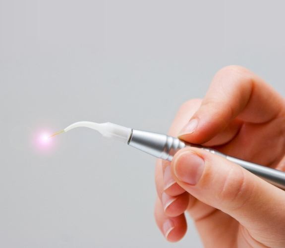 Hand holding a silver dental laser device