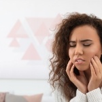 Woman touching her face and wincing in pain