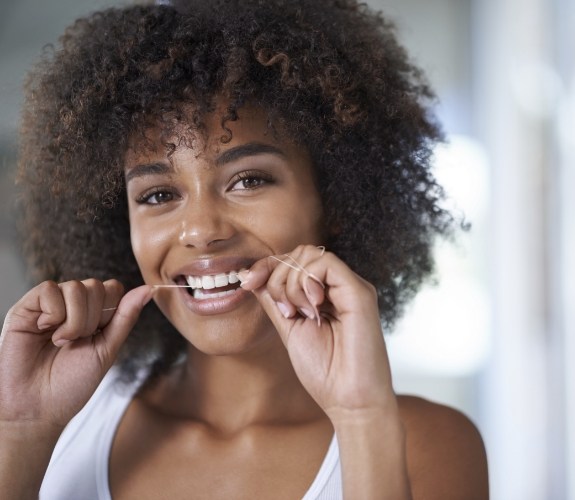 Woman smiling while flossing her teeth