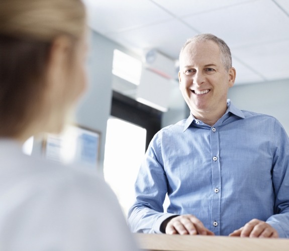 Man smiling at dental office receptionist