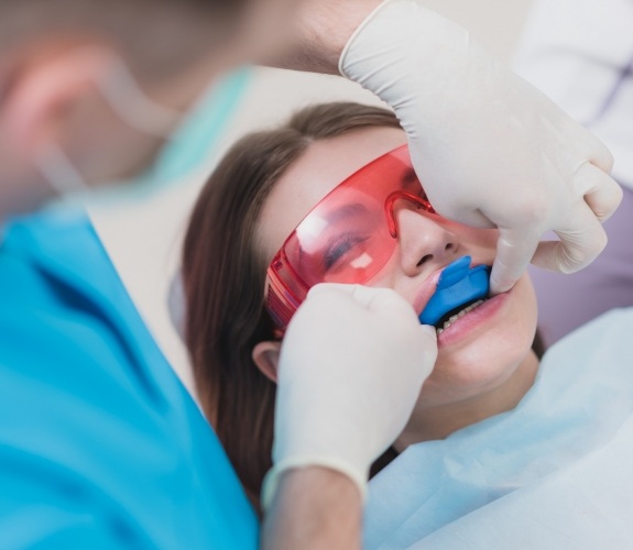 Young woman in dental chair having fluoride trays placed on her teeth