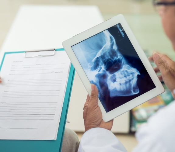 Dentist looking at tablet showing side profile X ray of head