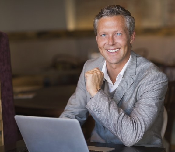 Man sitting at desk with laptop looking for dentist reviews in South Elgin