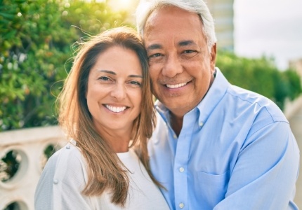 Man and woman sitting on outdoor bench and smiling on sunny day