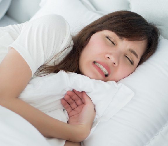 Woman wincing while laying in bed